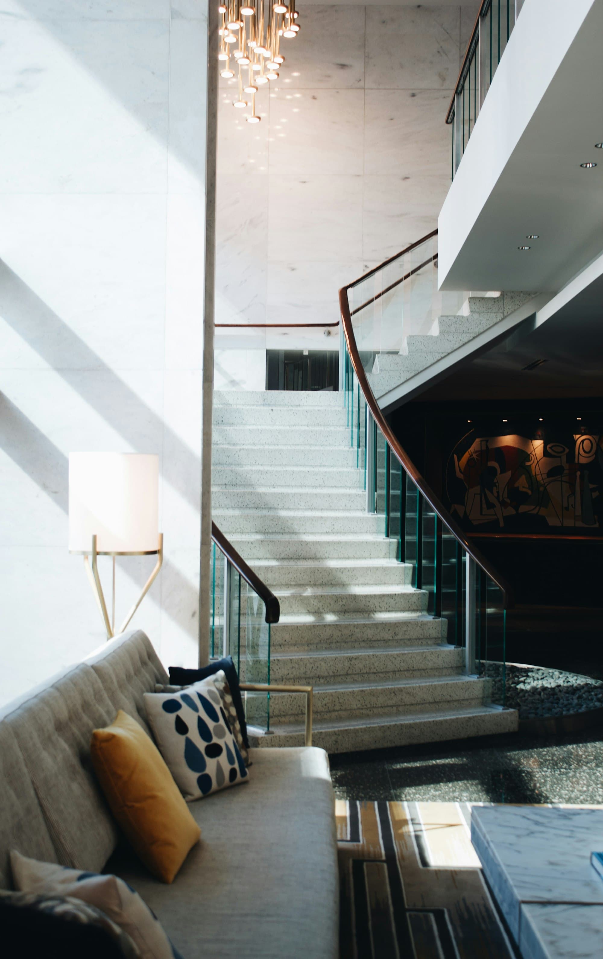 Warm, sunlit hotel staircase with marble steps and a soft seating area