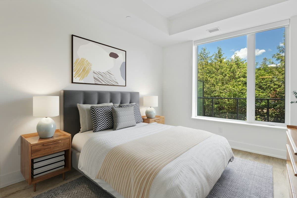 Bright bedroom with a view of trees and the city