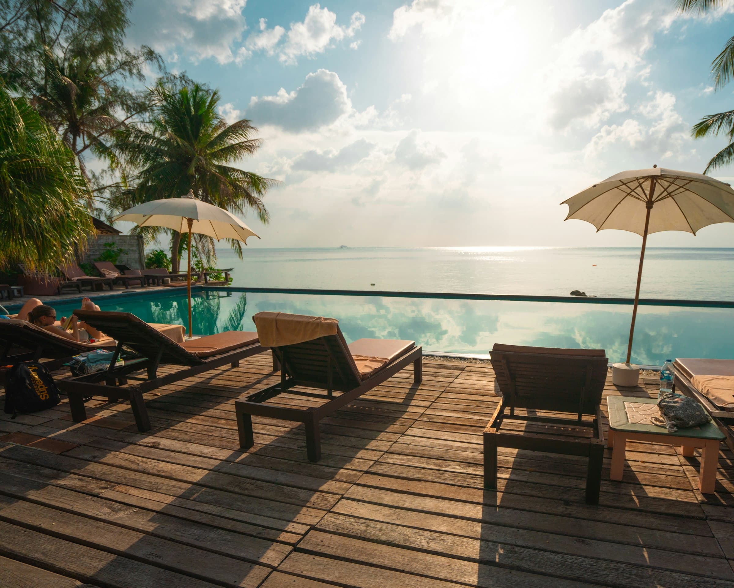 Sunlit pool deck with loungers overlooking the ocean at golden hour