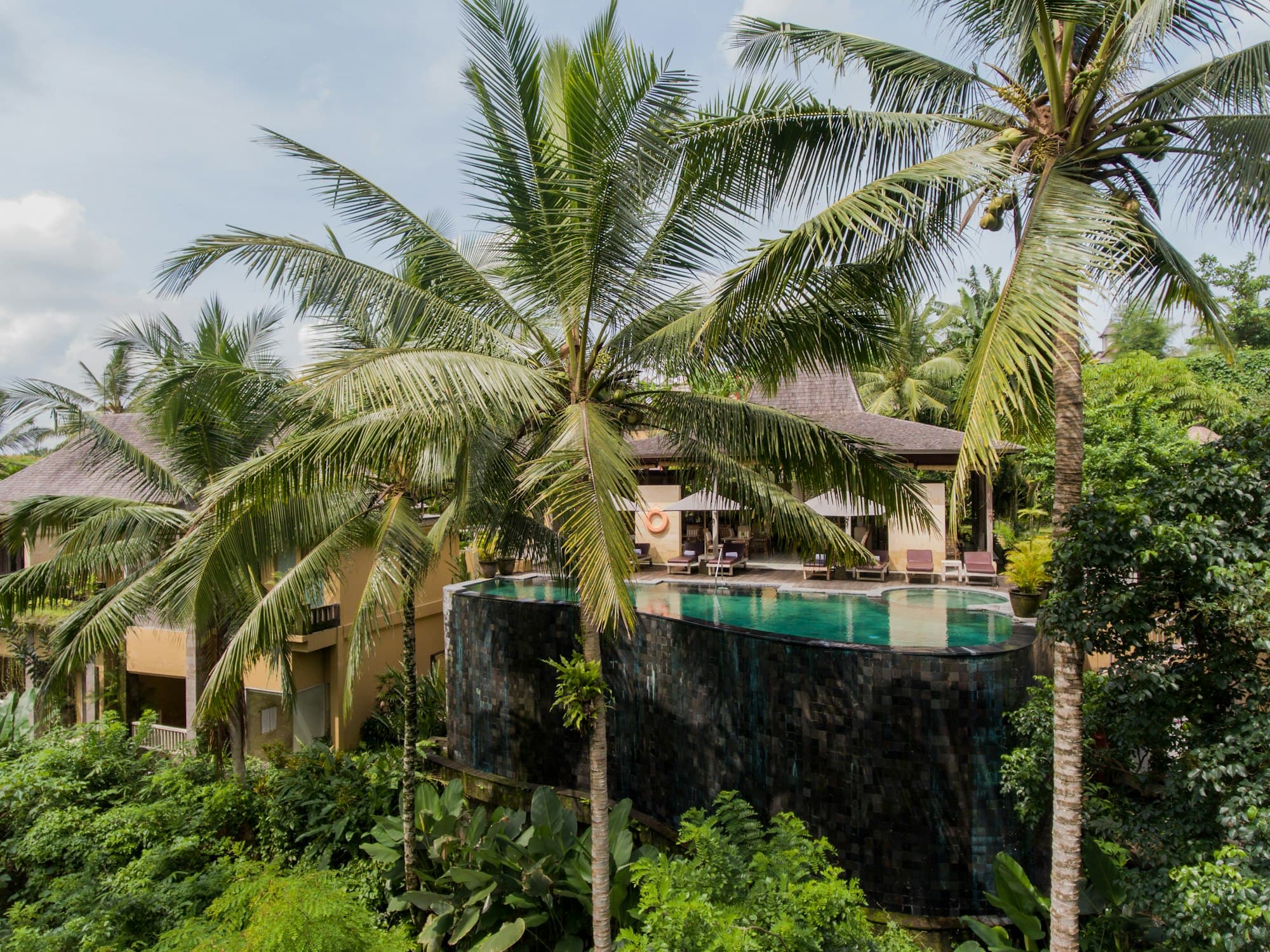 Aerial view of a dark-tiled infinity pool at a jungle villa